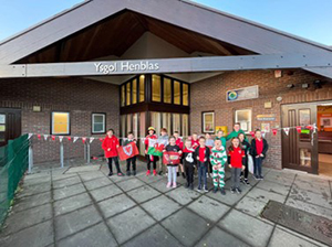 a group of children dressed in Welsh or red clothes in front of the school