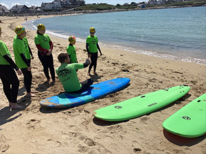 Children by the sea wearing wetsuits having a surfing lesson